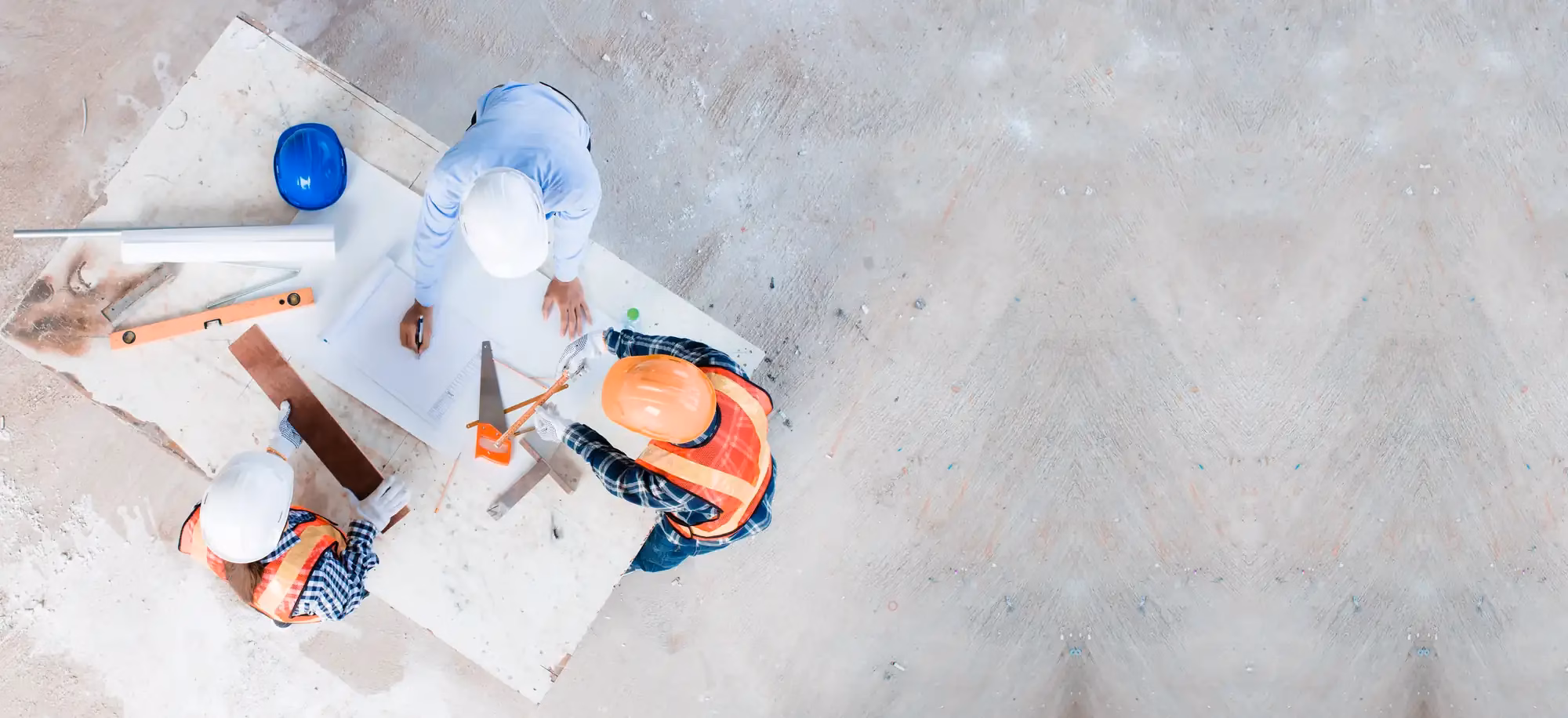 Site engineer and construction workers in hard hats reviewing drawings at a plan table